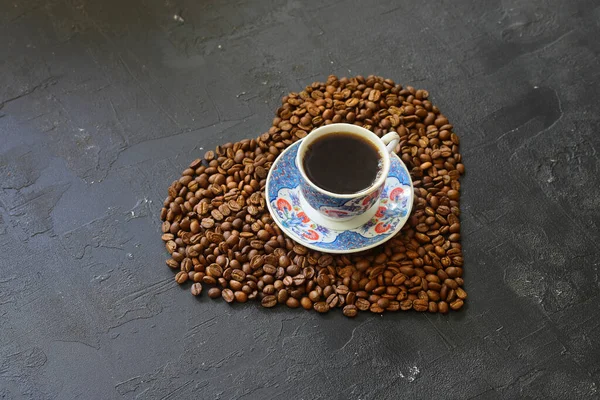 Heart coffee. Roasted coffee beans in the shape of heart on bright stone background. Concept of coffee love, Valentines Day, good mood, gift.