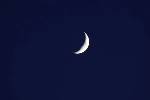 new moon or crescent moon up close in a dark blue night sky