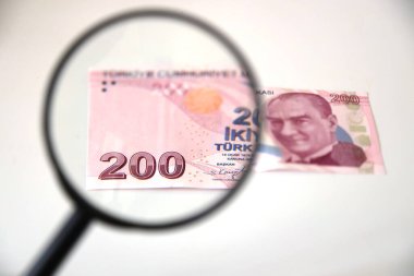 Banknotlar bir hesap makinesi ve büyüteç ile bir masaya yayılmış.