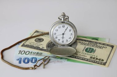 Dollar and old clock. Selective Focus.