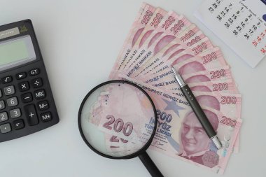 Turksh Lira banknotes of various color, pattern and value on white background. with magnifying glass