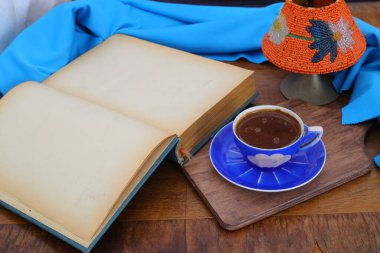 Morning coffee. Cozy composition: a cup of coffee on an open book. Still life concept. Copy space