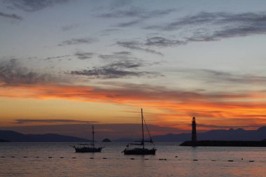 Gün ışığında deniz manzarası. Deniz feneri ve sahilde yelkenliler. Deniz kenti Turgutreis ve muhteşem güneş ışığı