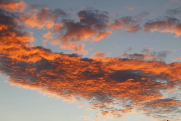 Dramatic red and orange sky and clouds abstract background. Red-orange clouds on sunset sky. Warm weather background. Art picture of sky at dusk. Sunset abstract background. Dusk and dawn concept