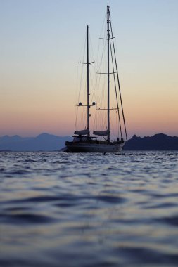 Bodrum, Hindi. 14 Ağustos 2022, gün batımında tek başına yelkenli. Yansımalı atmosferik deniz manzarası