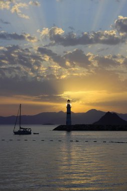 Gün ışığında deniz manzarası. Deniz feneri ve sahilde yelkenliler. Deniz kenti Turgutreis ve muhteşem güneş ışığı