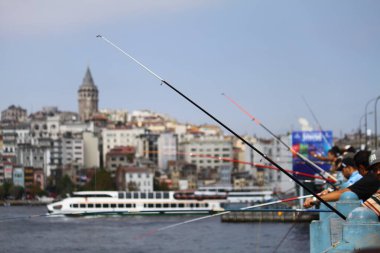 Galata Köprüsü 'nde, balıkçılar oltalarıyla İstanbul manzarası önünde görülüyor. Seçici Odaklanma.