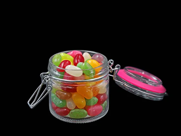 Open glazen pot van kleurrijke Jelly Beans geïsoleerd op zwarte achtergrond — Stockfoto