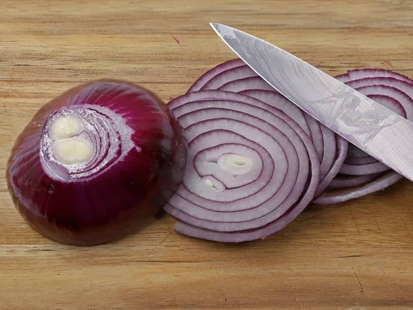 Nahaufnahme frisch geschnittener roter Zwiebeln mit Messer auf Holzschneidebrett — Stockfoto