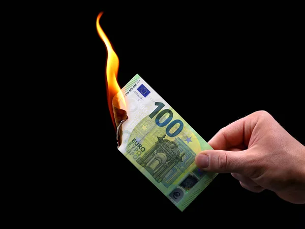 Male hand holds a burning 100 euro banknote isolated on black background, concept image of inflation — Stock Photo, Image