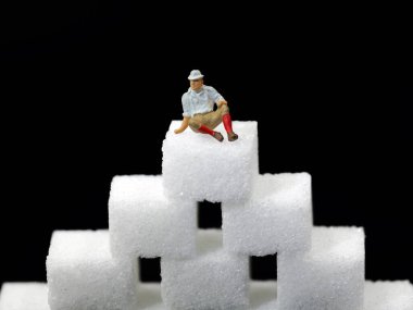 Şeker küplerinin üzerinde oturan yaşlı adam, şeker tüketiminin yaşlılıkta artmasının konsept görüntüsü ve bundan kaynaklanan hastalıklar