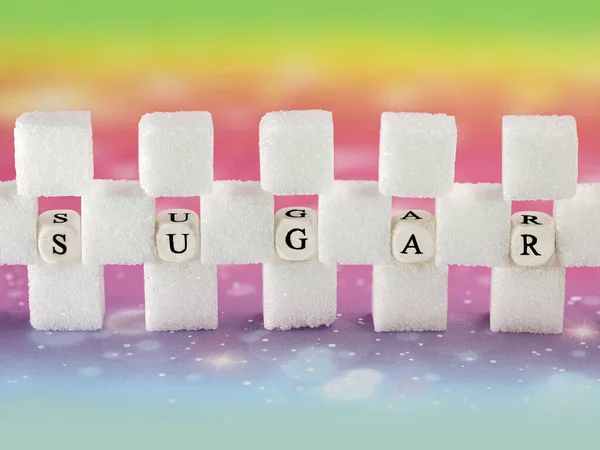 Стіна цукрових кубиків з текстом на кубиках літери ізольовані на барвистому фоні, концептуальне зображення споживання цукру населення та отриманої цукрової залежності — стокове фото