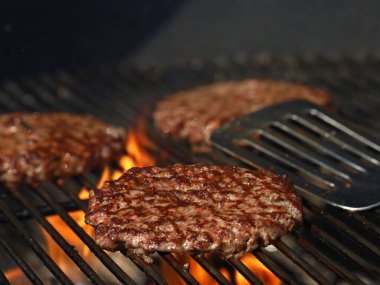 Izgarada taze ızgara biftek ızgarası ve arka planda paslanmaz çelik spatula.