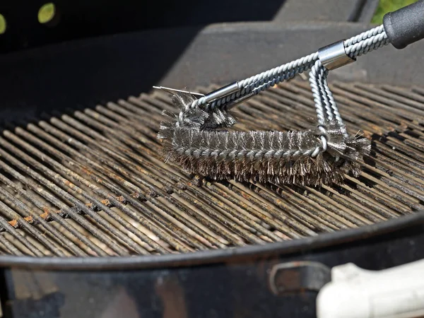 Cleaning a grill, dirty grill grate is cleaned with stainless steel grill brush — Stock Photo, Image