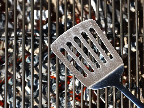 Boş ızgara ızgarasında paslanmaz çelik spatula parlayan kömürün üstünde ızgara, üst manzara. — Stok fotoğraf