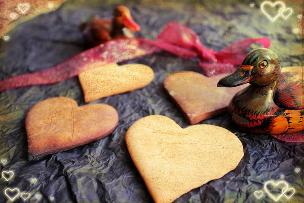 Fond Saint-Valentin avec biscuits au sucre en forme de coeur, vieux papier noir, canards et noeud de ruban rouge — Photo