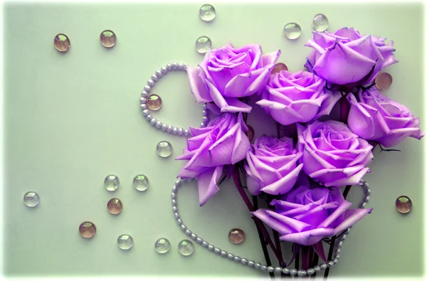 Рожеві троянди з перловою ниткою з бісеру на світло-блакитному фоні зі скляними кульками — стокове фото