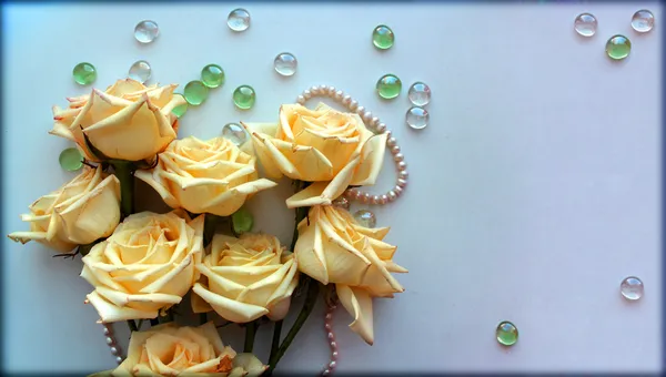 Rose gialle fiori con un filo di perle di perle su sfondo azzurro con sfere di vetro — Foto Stock