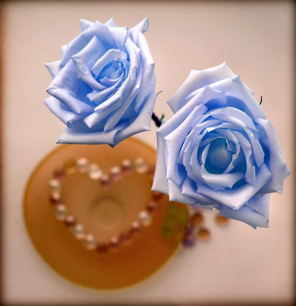 Дві сині троянди з серцем зі скляного бісеру на скляній тарілці — стокове фото