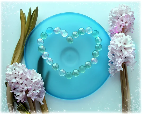 Квіти гіацинту з серцем з перлового бісеру на блакитній скляній тарілці — стокове фото