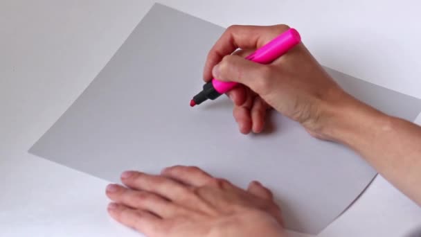 Жінка рука з олівцем малює рожеве серце на сірому папері — стокове відео