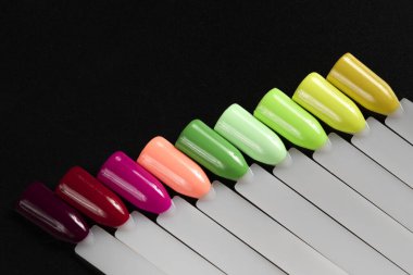 Siyah arka planda çok renkli tırnak uçları. Tırnaklar için manikür örneği. Çivi renk örnekleriyle palet. 