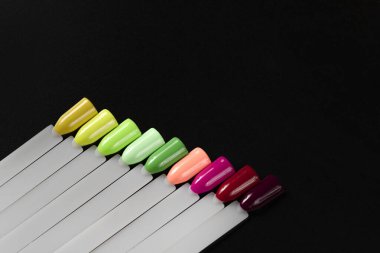 Siyah arka planda çok renkli tırnak uçları. Tırnaklar için manikür örneği. Çivi renk örnekleriyle palet. 