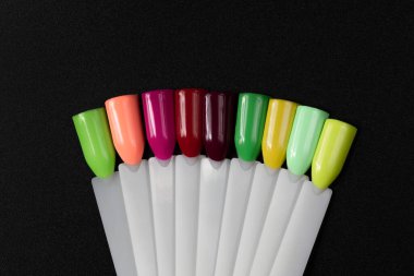 Siyah arka planda çok renkli tırnak uçları. Tırnaklar için manikür örneği. Çivi renk örnekleriyle palet. 