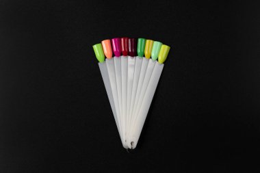 Siyah arka planda çok renkli tırnak uçları. Tırnaklar için manikür örneği. Çivi renk örnekleriyle palet. 