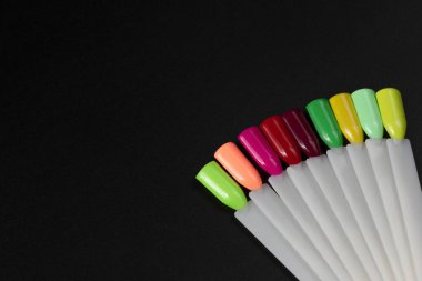Siyah arka planda çok renkli tırnak uçları. Tırnaklar için manikür örneği. Çivi renk örnekleriyle palet. 