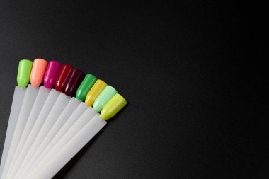 Siyah arka planda çok renkli tırnak uçları. Tırnaklar için manikür örneği. Çivi renk örnekleriyle palet. 