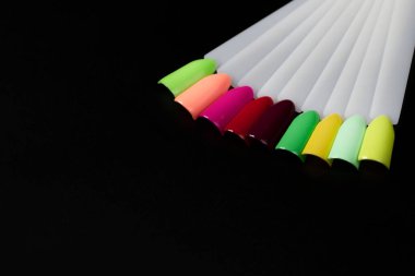 Siyah arka planda çok renkli tırnak uçları. Tırnaklar için manikür örneği. Çivi renk örnekleriyle palet. 