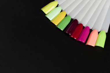 Siyah arka planda çok renkli tırnak uçları. Tırnaklar için manikür örneği. Çivi renk örnekleriyle palet. 