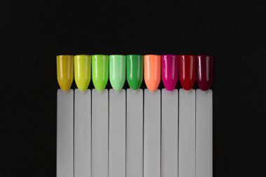 Siyah arka planda çok renkli tırnak uçları. Tırnaklar için manikür örneği. Çivi renk örnekleriyle palet. 