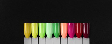 Siyah arka planda çok renkli tırnak uçları. Tırnaklar için manikür örneği. Çivi renk örnekleriyle palet. 