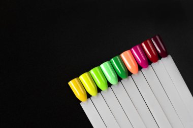 Siyah arka planda çok renkli tırnak uçları. Tırnaklar için manikür örneği. Çivi renk örnekleriyle palet. 