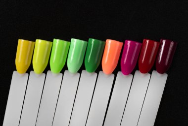 Siyah arka planda çok renkli tırnak uçları. Tırnaklar için manikür örneği. Çivi renk örnekleriyle palet. 