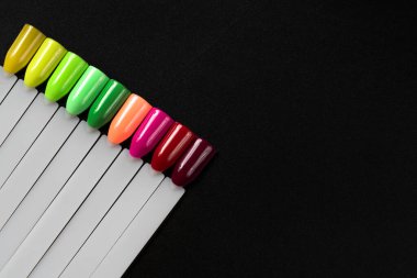 Siyah arka planda çok renkli tırnak uçları. Tırnaklar için manikür örneği. Çivi renk örnekleriyle palet. 