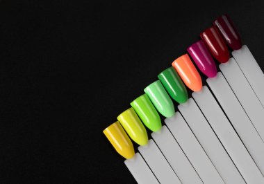 Siyah arka planda çok renkli tırnak uçları. Tırnaklar için manikür örneği. Çivi renk örnekleriyle palet. 