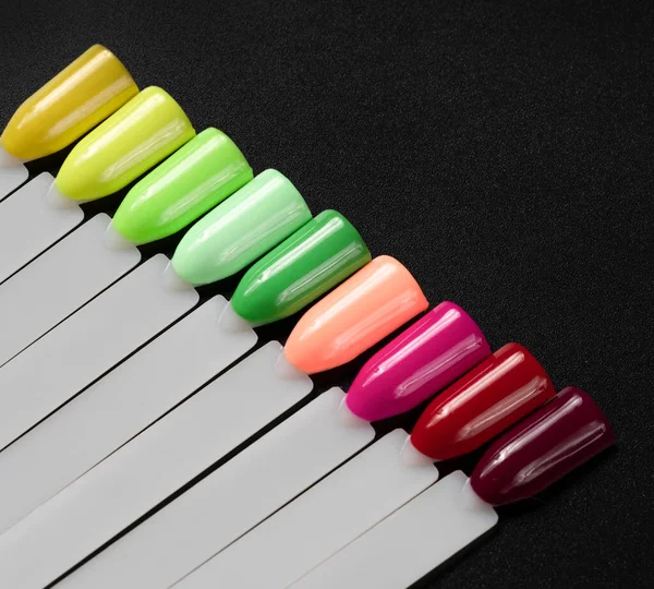 Siyah arka planda çok renkli tırnak uçları. Tırnaklar için manikür örneği. Çivi renk örnekleriyle palet. 