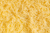 Reszelt sajt háttér textúra. Sárga aprított sajt. Közelről a csúcsra.