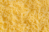 Reszelt sajt háttér textúra. Sárga aprított sajt. Közelről a csúcsra.
