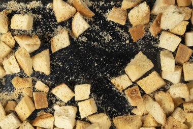 Siyah arka planda pişmiş krakerler. Yakın plan. Kurutulmuş küçük ekmek parçaları. Ekmek kırıntıları.