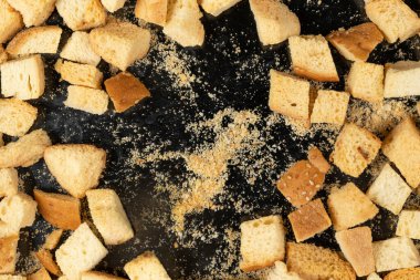 Siyah arka planda pişmiş krakerler. Yakın plan. Kurutulmuş küçük ekmek parçaları. Ekmek kırıntıları.