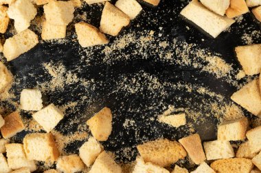 Siyah arka planda pişmiş krakerler. Yakın plan. Kurutulmuş küçük ekmek parçaları. Ekmek kırıntıları.