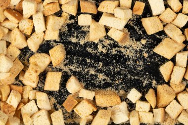 Siyah arka planda pişmiş krakerler. Yakın plan. Kurutulmuş küçük ekmek parçaları. Ekmek kırıntıları.