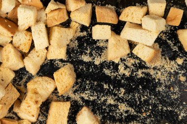 Siyah arka planda pişmiş krakerler. Yakın plan. Kurutulmuş küçük ekmek parçaları. Ekmek kırıntıları.