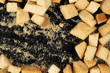 Siyah arka planda pişmiş krakerler. Yakın plan. Kurutulmuş küçük ekmek parçaları. Ekmek kırıntıları.