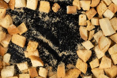 Siyah arka planda pişmiş krakerler. Yakın plan. Kurutulmuş küçük ekmek parçaları. Ekmek kırıntıları.