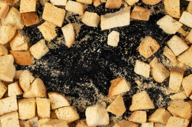 Siyah arka planda pişmiş krakerler. Yakın plan. Kurutulmuş küçük ekmek parçaları. Ekmek kırıntıları.